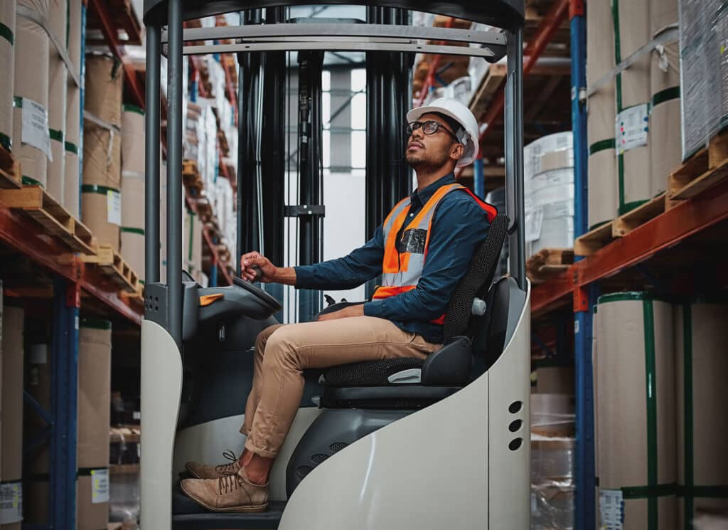 Happy forklift driver focused on carefully transporting stock