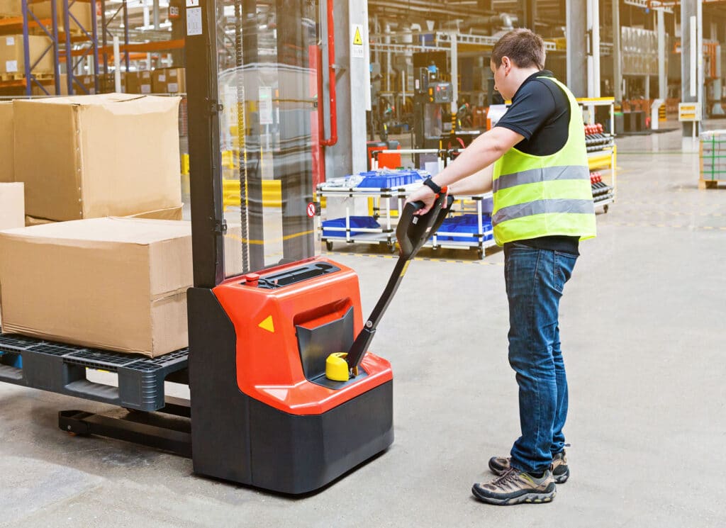 Storehouse employee in uniform working on forklift in modern automatic warehouse