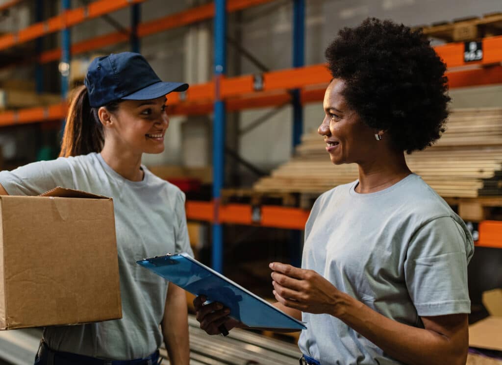 Happy female workers communicating while working in distribution warehouse